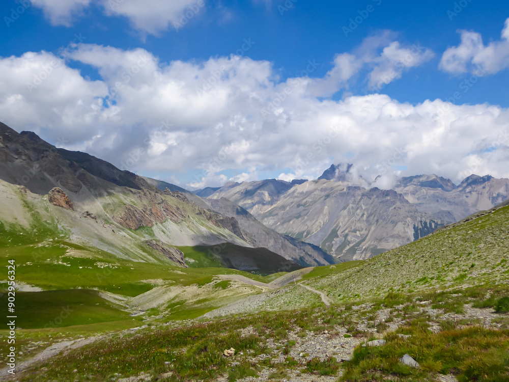 Alpine green pasture with panoramic view of mountains and hills in valley Valle Stura in Colle Del Puriac, Piemonte, Italy, Europe. Hiking tour in Italian Alps in summer. Peaceful serene atmosphere