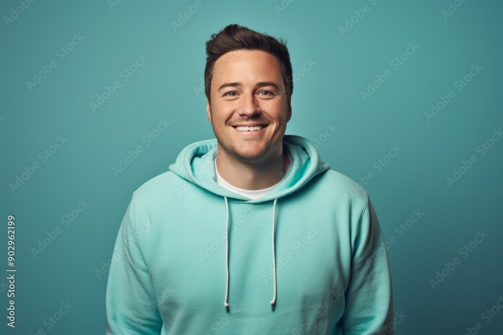 Portrait of a satisfied man in his 30s wearing a zip-up fleece hoodie in front of pastel teal background Portrait of a satisfied man in his 30s wearing a zip-up fleece hoodie in front of pastel teal background