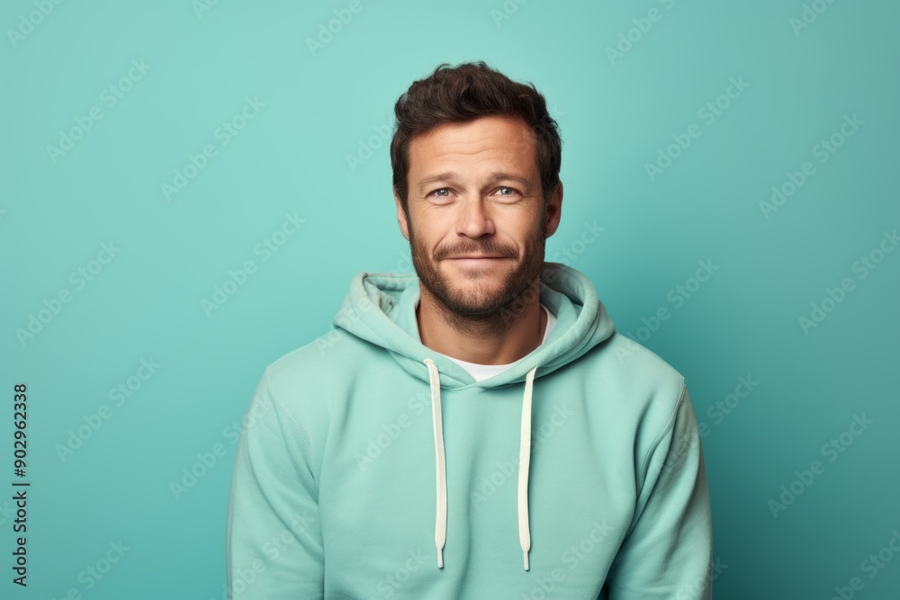 Portrait of a satisfied man in his 30s wearing a zip-up fleece hoodie over pastel teal background Portrait of a satisfied man in his 30s wearing a zip-up fleece hoodie over pastel teal background