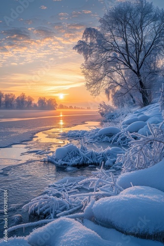 A beautiful winter scene with a frozen river and a tree in the background. The sun is setting, casting a warm glow on the water. The snow-covered ground and the frozen river create a serene