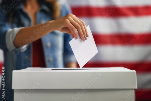 Close up shot of polling box standing on table in polling station. American female voter with kid on hands puts bulletin into box. Political races of US presidential candidates. National Election Day.
