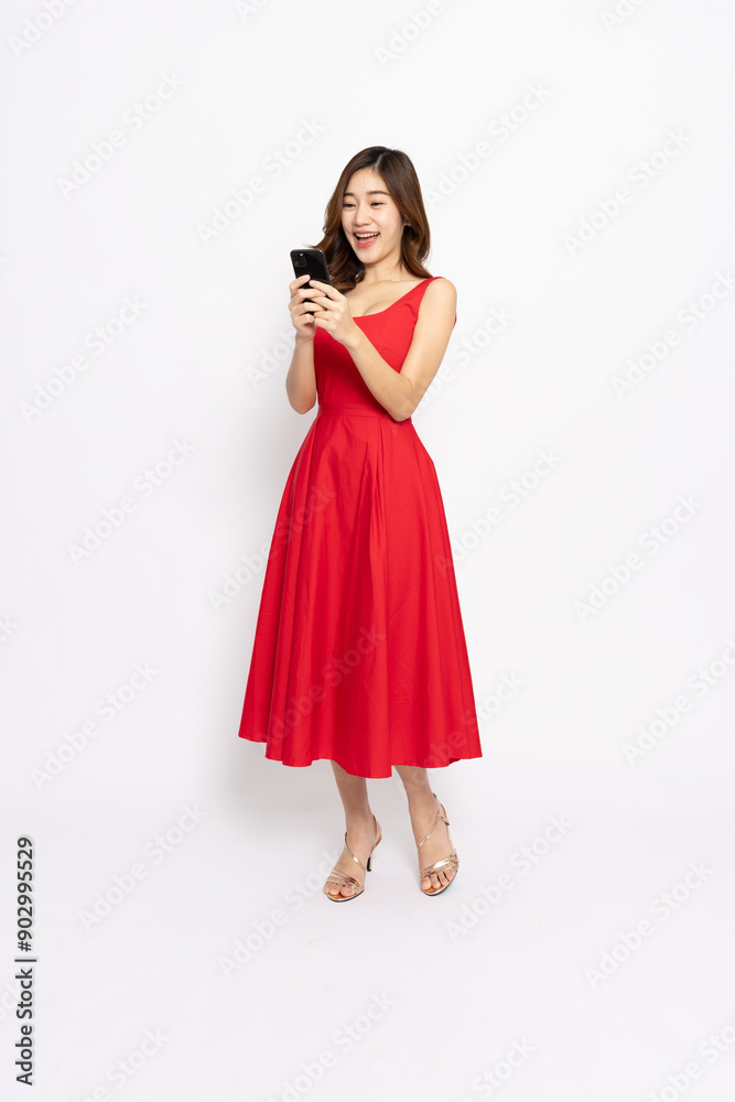 Happy Young Asian woman in red dress standing and using mobile phone isolated on white background, Full body composition Happy Young Asian woman in red dress standing and using mobile phone isolated on white background, Full body composition