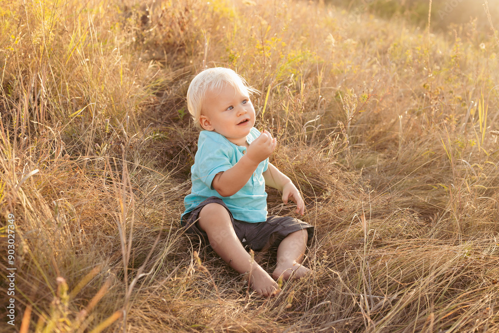 Little boy in nature in summer playing on grass with sun rays on sunset Little boy in nature in summer playing on grass with sun rays on sunset