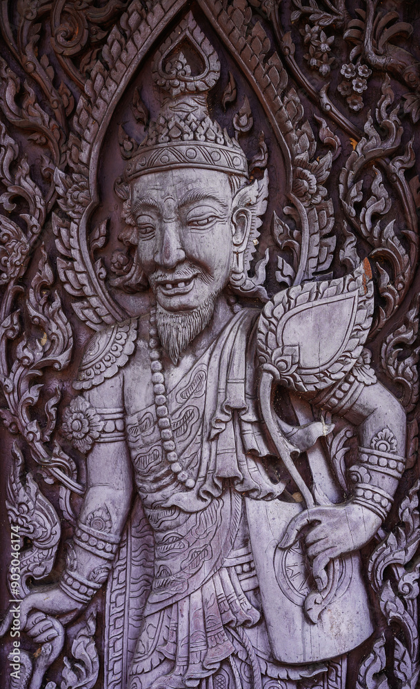 Obraz premium Wood carvings hermit are made into gate doors of temple at Wat Phra That Ket Kaew Chulamanee, Chaiyaphum, Thailand.Traditional Thai sculpture style. Vertical.