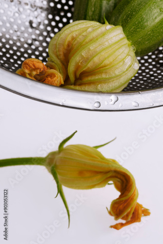 Baby zucchini and zucchini flowers in a metal colander