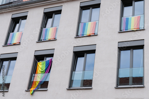 Vibrant rainbow flags adorn the balconies of an apartment building, celebrating diversity and love during Pride Month.