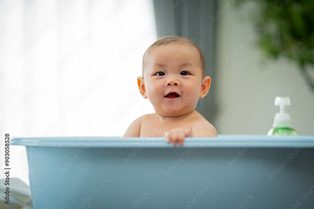 A baby is in a bathtub with a bottle of lotion next to it. The baby is smiling and looking at the camera A baby is in a bathtub with a bottle of lotion next to it. The baby is smiling and looking at the camera