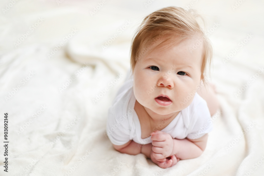 Portrait of a cute Caucasian 3-month-old baby girl during tummy time looking at the camera with the white background. Copy space. Portrait of a cute Caucasian 3-month-old baby girl during tummy time looking at the camera with the white background. Copy space.
