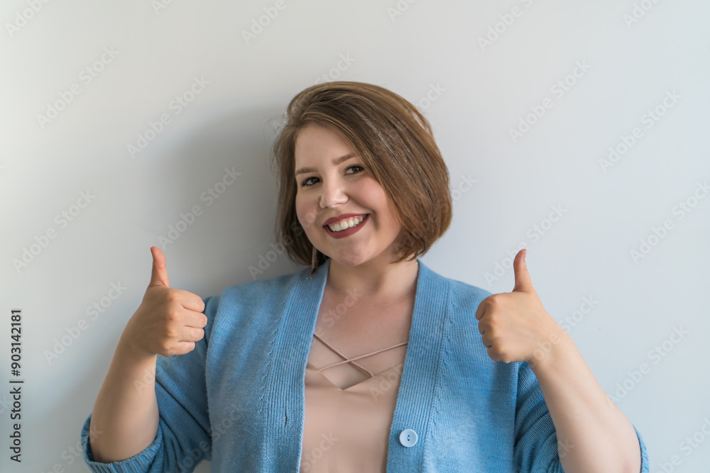 Smiling woman showing thumbs up with positive facial expression. Happy female expressing approval, positive feedback, agreement concept. Smiling woman showing thumbs up with positive facial expression. Happy female expressing approval, positive feedback, agreement concept.