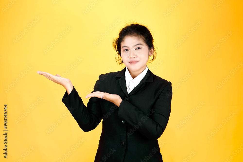 Portrait of a confident young Asian businesswoman wearing black suit isolated on yellow background. Portrait of a confident young Asian businesswoman wearing black suit isolated on yellow background.