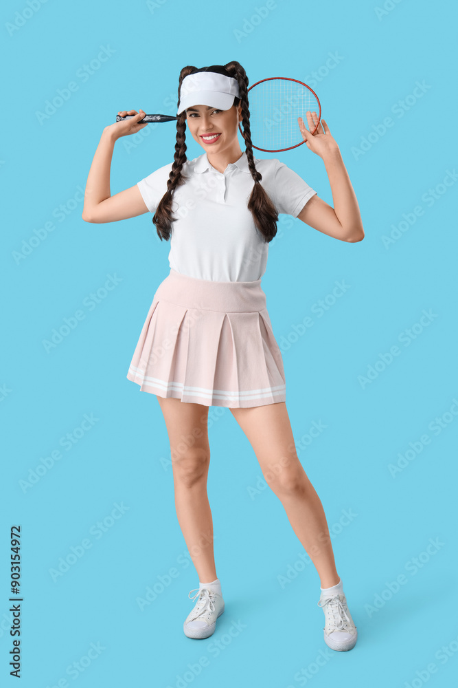 Beautiful young happy badminton player with braids holding racket on blue background Beautiful young happy badminton player with braids holding racket on blue background