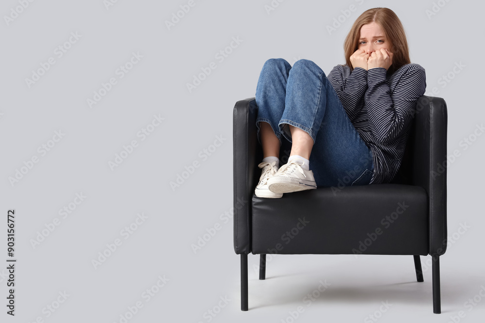 Young woman having panic attack in armchair on light background Young woman having panic attack in armchair on light background