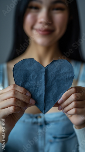 Smiling young woman behind a large blank navy blue heart. Copy space. photo