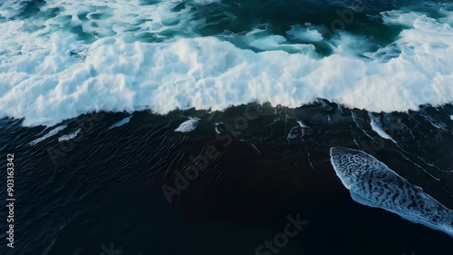 Aerial view of turbulent ocean waves swirling over a black sand beach photo