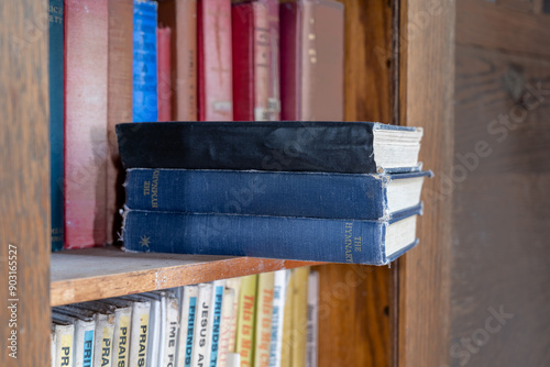 Εκτύπωση καμβά Three old blue colored hymn books sitting on an old dusty bookshelf
