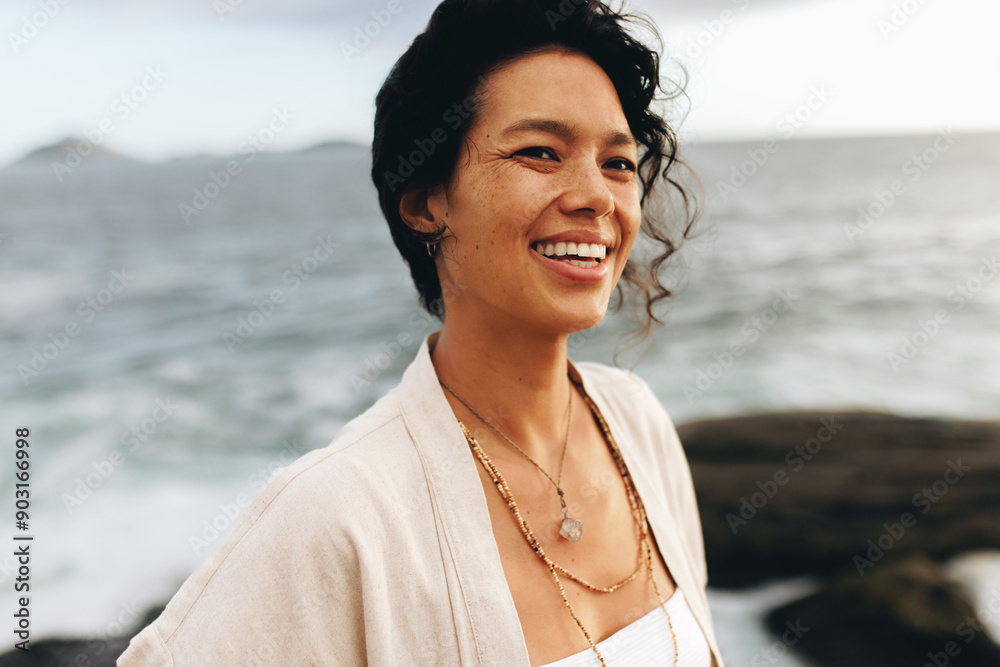 Carefree woman enjoying a beach vacation at dusk, smiling happily by the seaside Carefree woman enjoying a beach vacation at dusk, smiling happily by the seaside