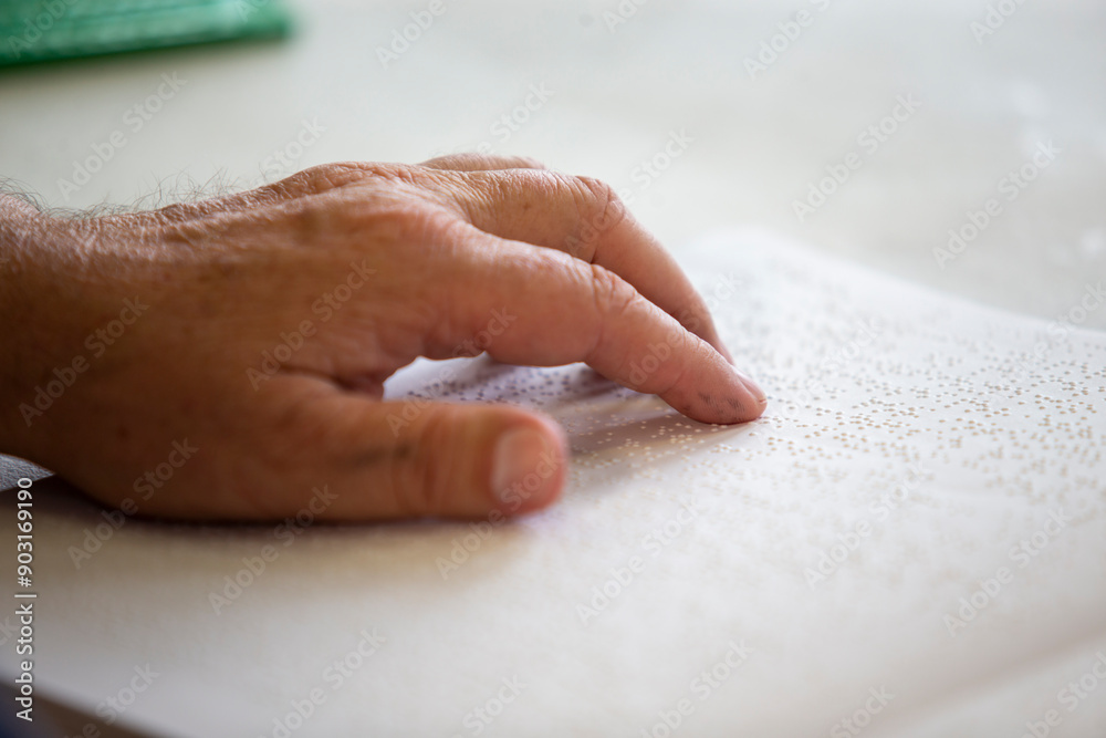 Detail of fingers reading a book in braille. Reading for the disabled with blindness