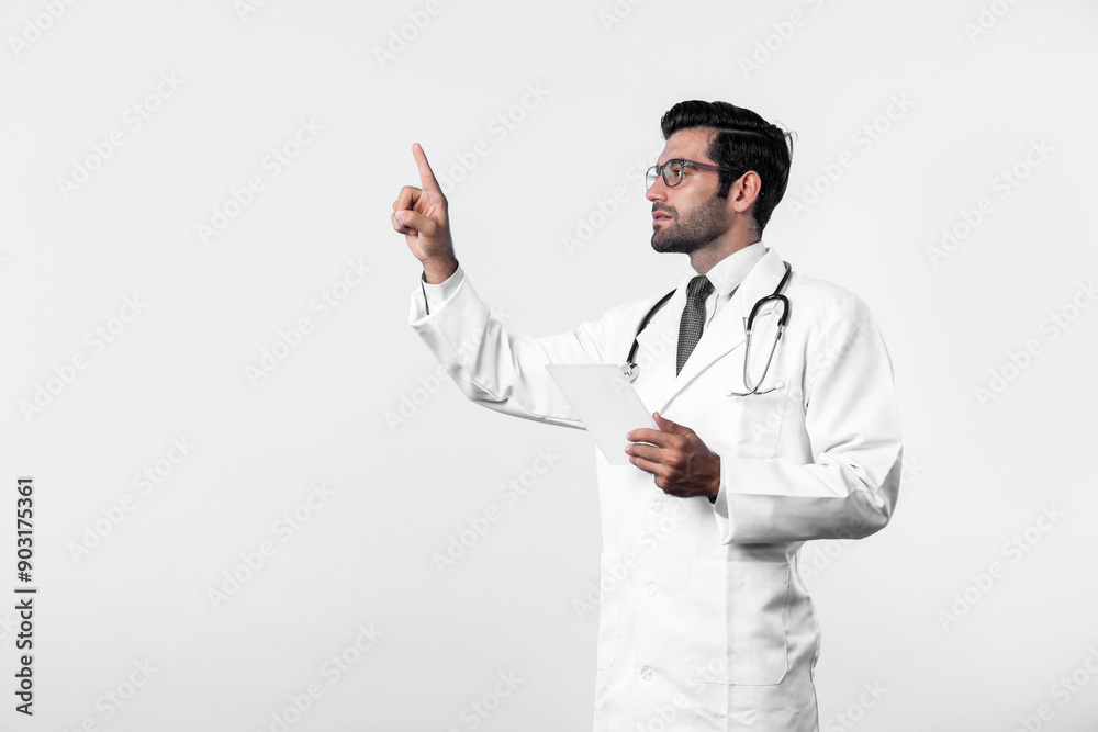 Caucasian smart doctor pointing finger while standing at white background and wearing lab coat. Skilled specialist doctor using medical technology while pointing and holding health data. Deviation. Caucasian smart doctor pointing finger while standing at white background and wearing lab coat. Skilled specialist doctor using medical technology while pointing and holding health data. Deviation.