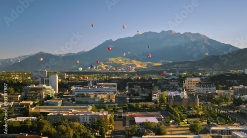 Cluster of hot air balloons rising over city at sunrise - drone shot moving in photo