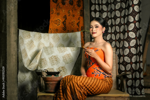 Young Indonesian women or fashion models wearing traditional Indonesian clothing or attire with batik motifs from Indonesian culture. Making or painting batik cloth. Making batik cloth. photo