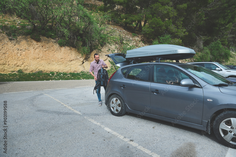 Man preparing for road trip with car trunk luggage on a scenic highway Man preparing for road trip with car trunk luggage on a scenic highway