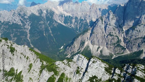 An awe-inspiring aerial view of Vršič Pass (Vršič sedlo) in the Slovenian Alps, captured by a drone. This remarkable image highlights the winding mountain road snaking through rugged peaks, lush green photo