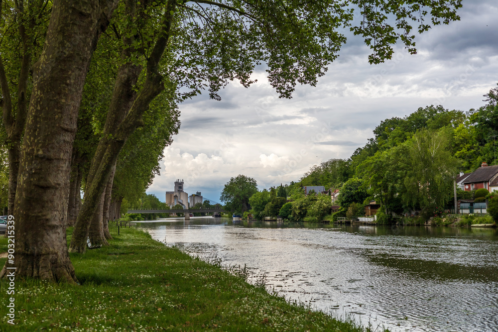 Tranquil Riverside Pathway and Industrial Silos in Nemours, France
