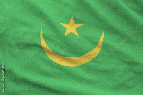 Mauritania flag depicted on folded wavy fabric of old cloth close up photo