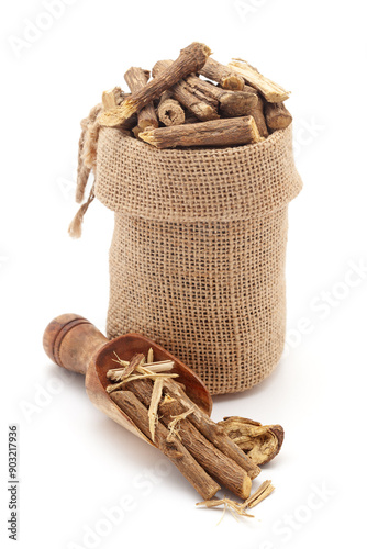 Close-up of Dry Organic Liquorice or Mulethi (Glycyrrhiza glabra) roots, in a jute bag and on a scoop, Isolated on a white background. photo