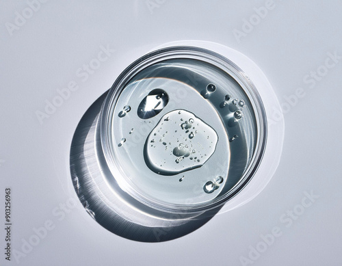 Top-down view of a petri dish with liquid or serum inside it, bubbles, splash around the petri dish, hard light