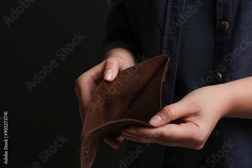 Woman with empty wallet on dark background, closeup photo