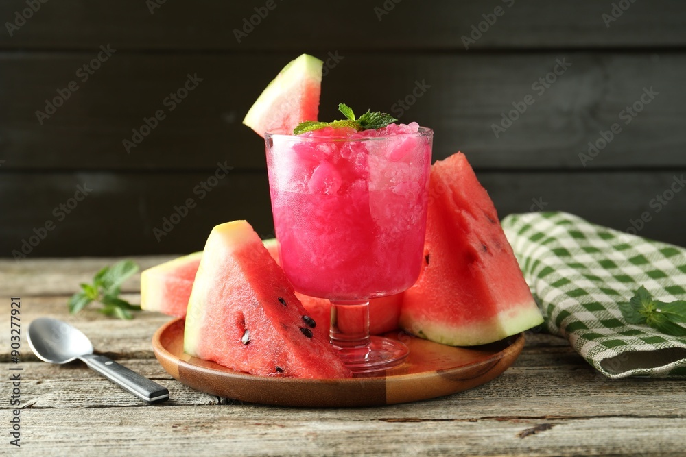 Tasty watermelon sorbet in glass dessert bowl, fresh fruit, mint and spoon on wooden table Tasty watermelon sorbet in glass dessert bowl, fresh fruit, mint and spoon on wooden table