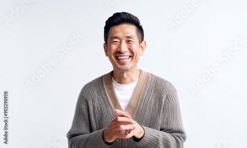 portrait of a happy Japanese man in his 40s wearing a chic cardigan against a white background