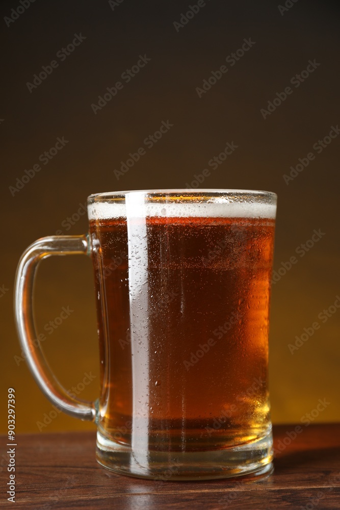 Mug with fresh beer on wooden table against dark background Mug with fresh beer on wooden table against dark background