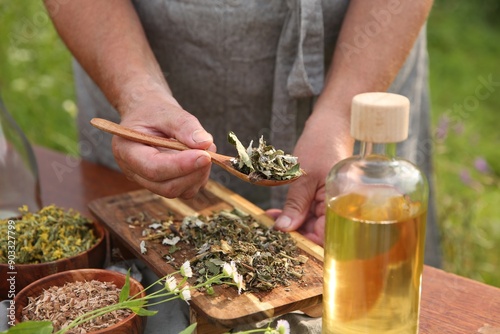 Senior woman making tincture at table outdoors, closeup photo