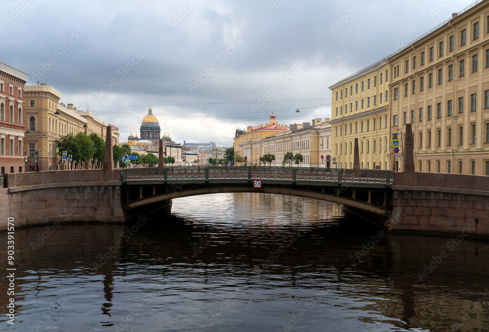 Naklejka premium View of St. Isaac's Cathedral and the Moika River embankment against the background of the Kissing Bridge on a summer morning, St. Petersburg, Russia