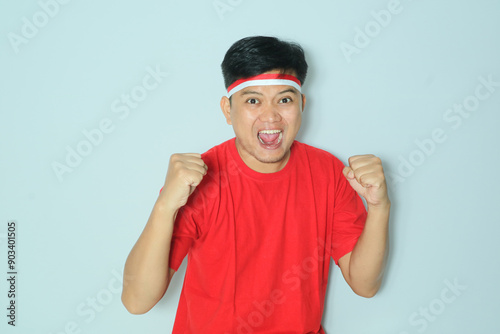 Indonesian man clenched both fist showing excitement when celebrating independence day. Wearing a red t-shirt photo