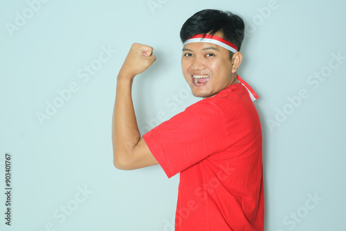 Indonesian man showing his arm muscle with enthusiastic expression. Wearing a red t-shirt photo