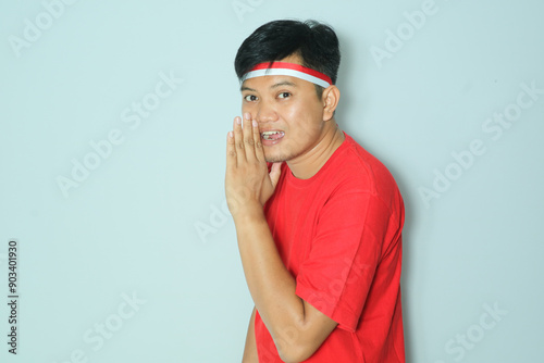 Indonesian man telling something pose with excited expression. Wearing a red t-shirt
