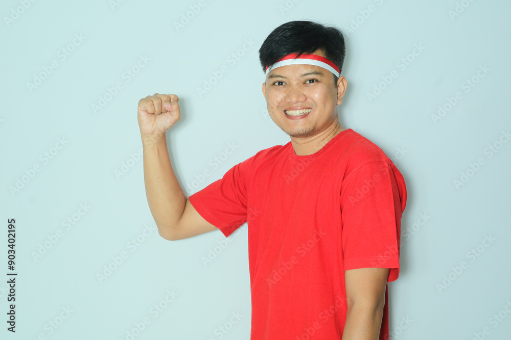 Indonesian man clenched fist showing a proud expression during independence day celebration. Wearing a red t-shirt Indonesian man clenched fist showing a proud expression during independence day celebration. Wearing a red t-shirt