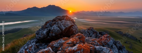 A river runs through the foreground, grass and rocks precede distant mountains photo