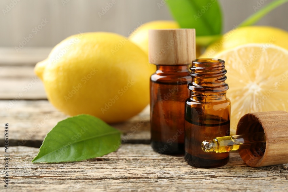 Essential oils in bottles, dropper, lemons and green leaves on wooden table, closeup Essential oils in bottles, dropper, lemons and green leaves on wooden table, closeup