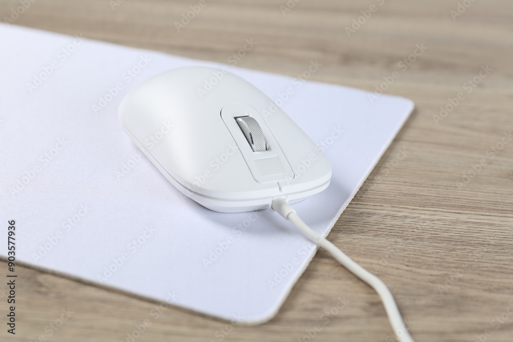 White computer mouse and mousepad on wooden table White computer mouse and mousepad on wooden table