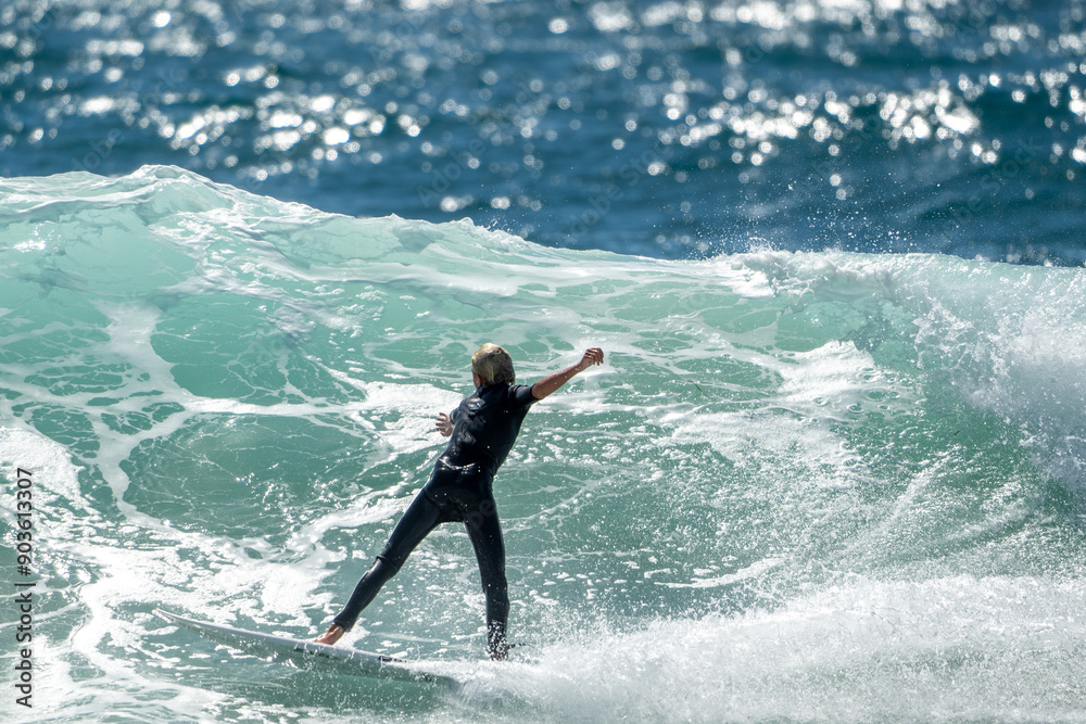 Caucasian male Australian surfer from behind surfing a wave