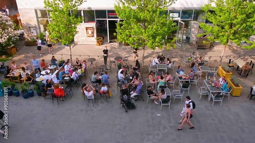 People eat at tables on the street, large companies sit on the terrace of a cafe or restaurant, a fashionable youth place, a view from above. Saint Petersburg, Russia - 23 June 2024