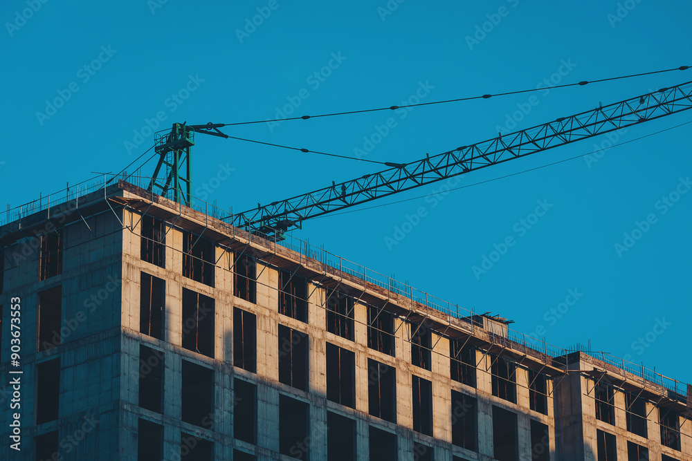 Fototapeta premium Building of the new high house by the crane. Industry new building business.