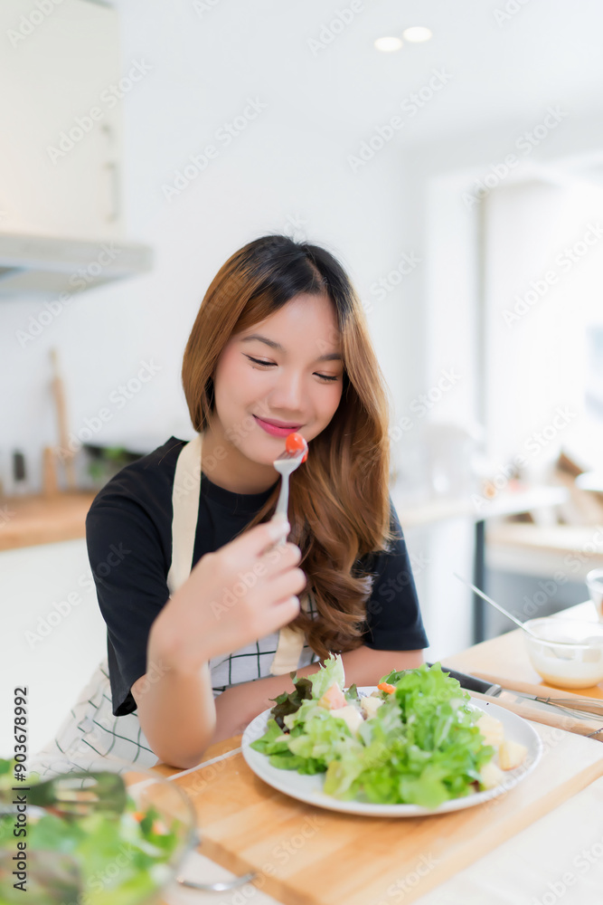 Young asian woman eating tomatoes in vegetables salad with happiness after mixing fresh vegetables salad with dressing and cooking healthy breakfast food in kitchen with healthy lifestyle at home Young asian woman eating tomatoes in vegetables salad with happiness after mixing fresh vegetables salad with dressing and cooking healthy breakfast food in kitchen with healthy lifestyle at home