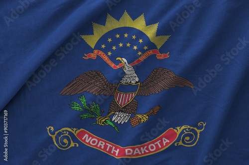 North Dakota US state flag depicted on folded wavy fabric of old cloth close up photo