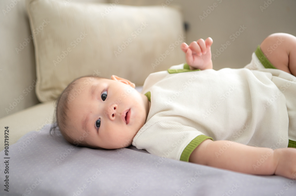 A tiny child smiles happily on the bed and mother is using a cotton bud to clean child ears A tiny child smiles happily on the bed and mother is using a cotton bud to clean child ears