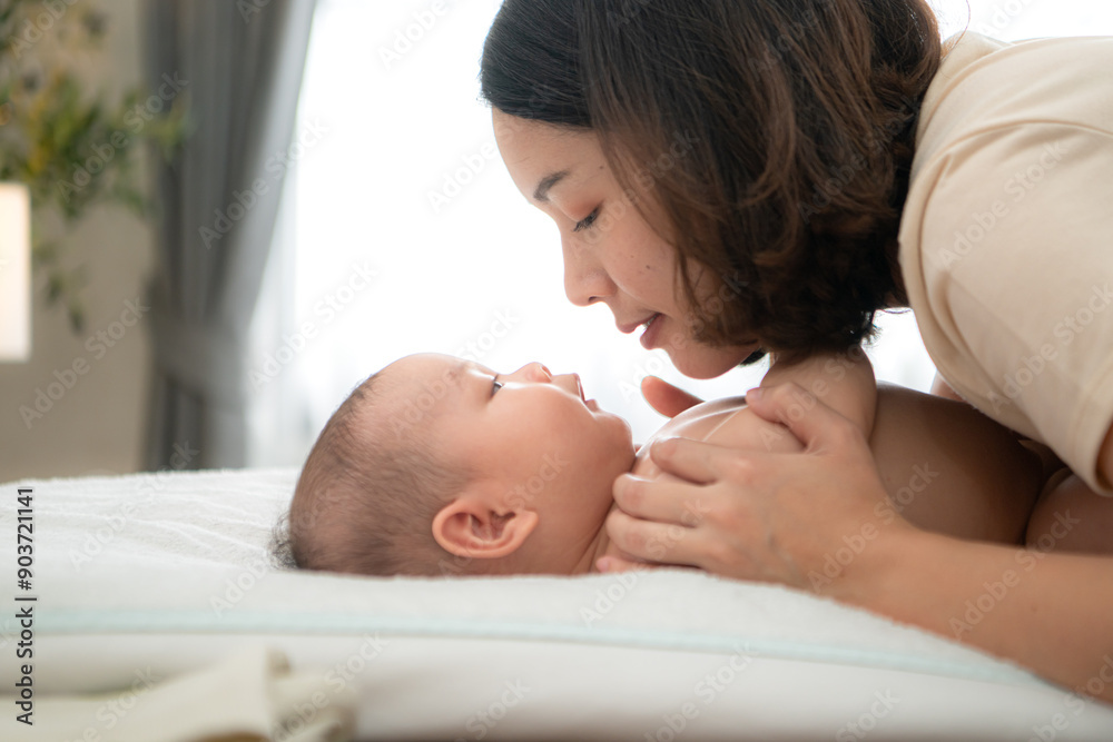 A tiny child smiles happily on the bed waiting for mother apply powder and put on clothes after taking a bath A tiny child smiles happily on the bed waiting for mother apply powder and put on clothes after taking a bath